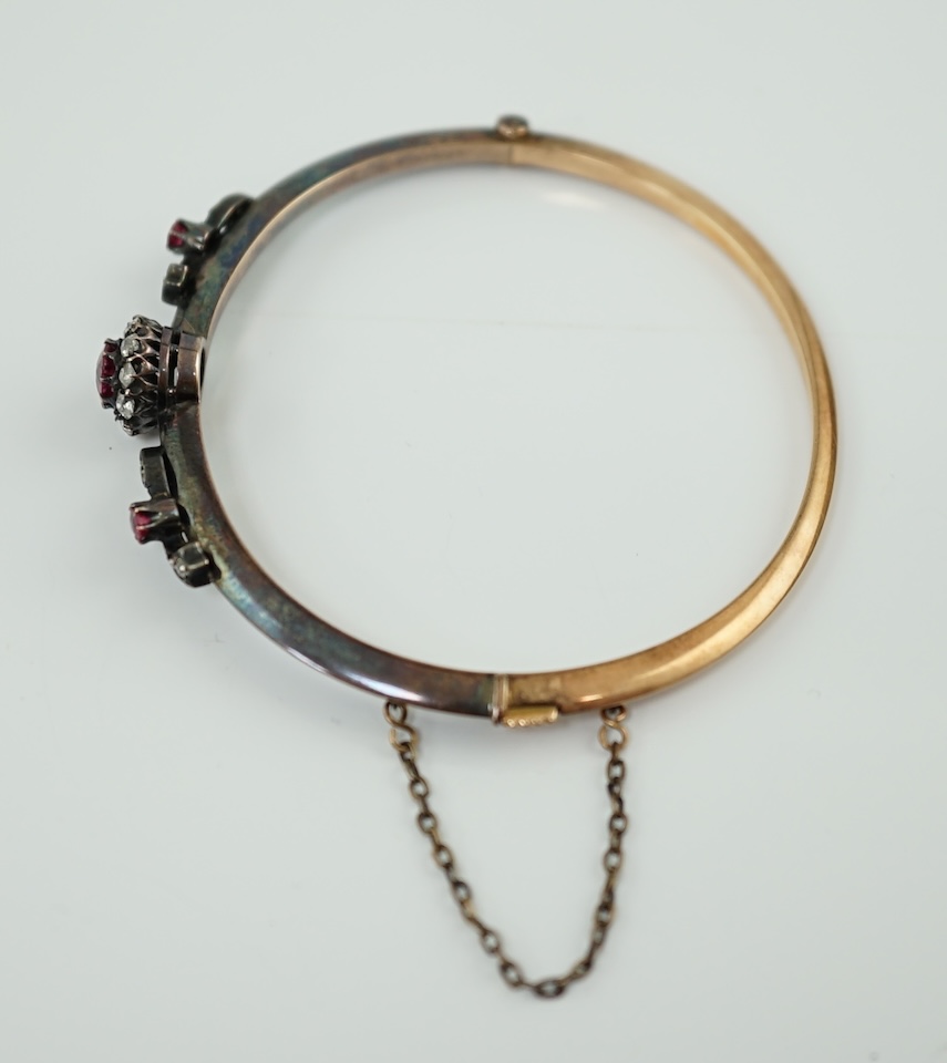 A late Victorian gold and silver, ruby and diamond cluster set hinged bangle